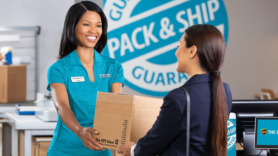 The UPS Store employee helping a customer with a package