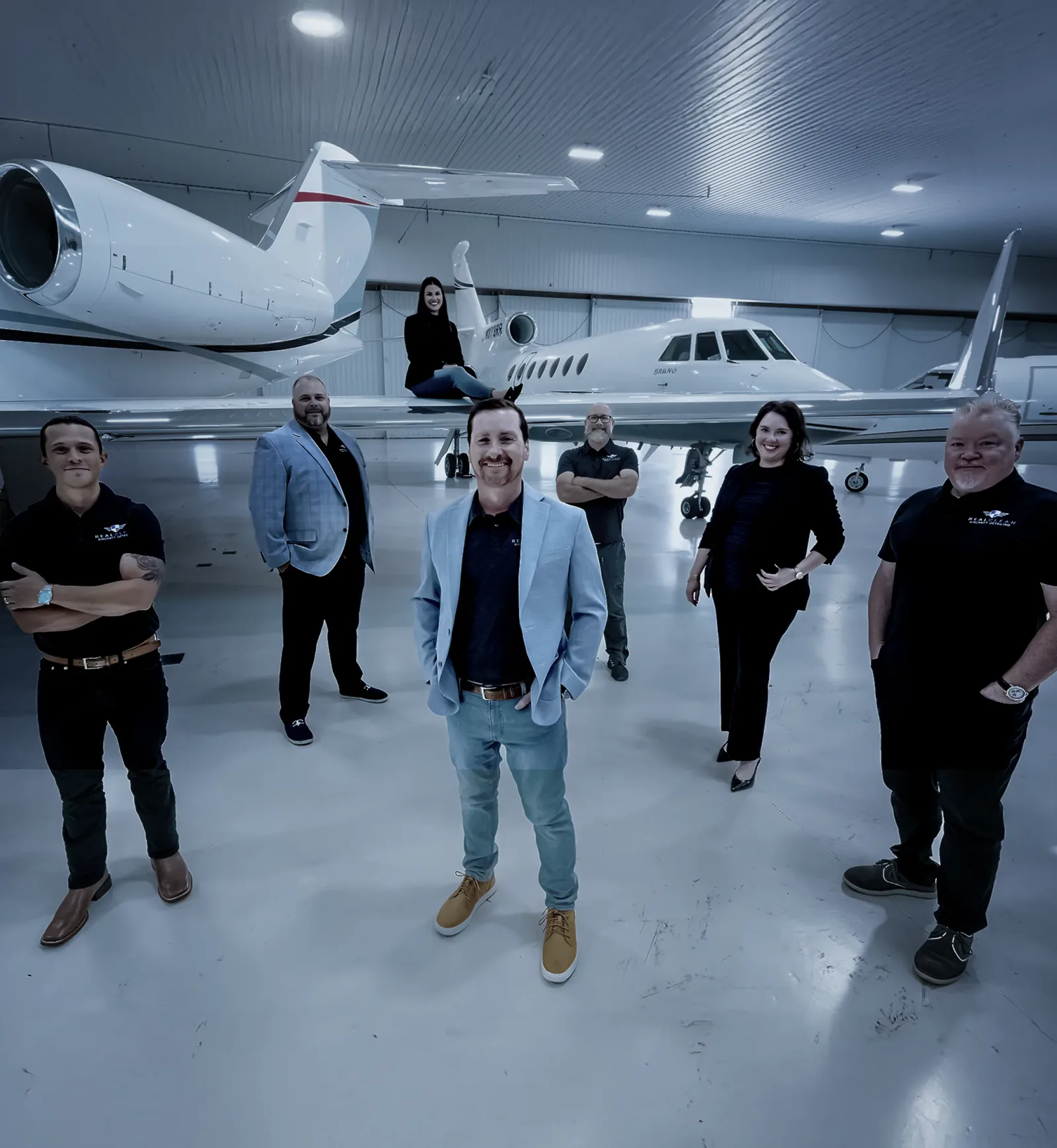RealClean team in an aircraft hangar beside private jets