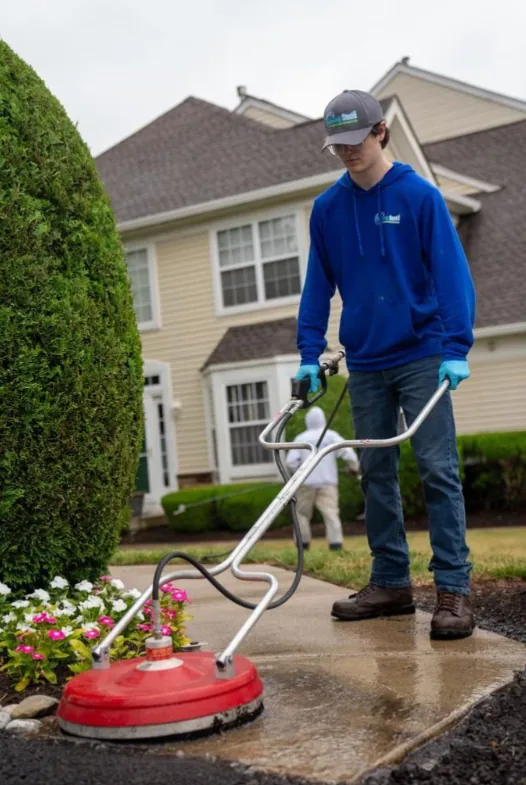 A technician pressure washing a residential driveway.