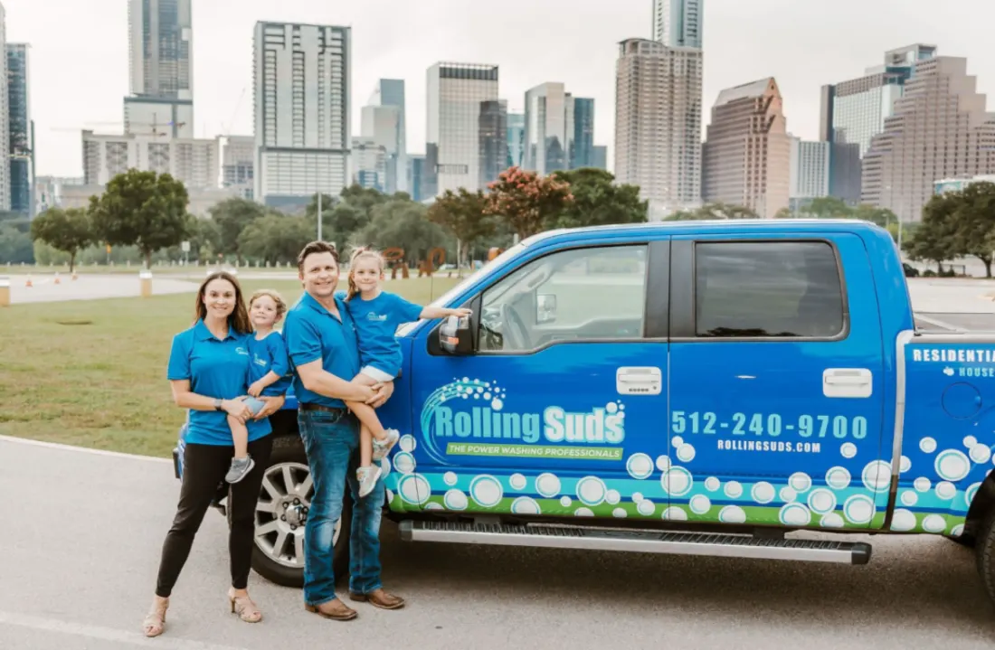 A family smiles beside a power washing service pickup.